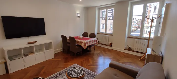 Séjour avec téléviseur et coin repas, vue sur les colombages